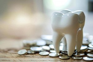 a porcelain tooth atop a pile of coins